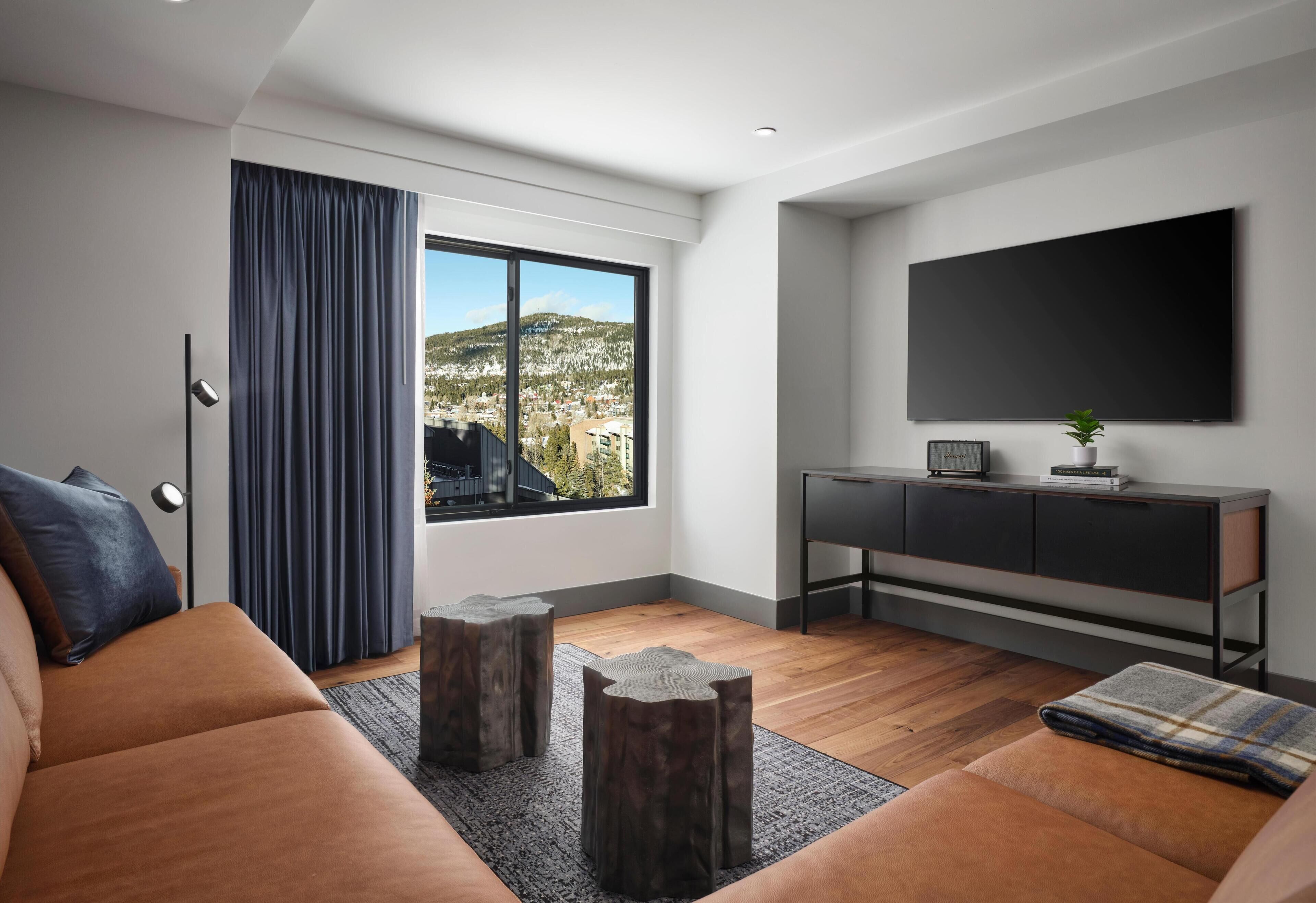 Una sala de estar moderna con un ventanal grande, un televisor de pantalla plana, un sofá y un mueble de consola minimalista.