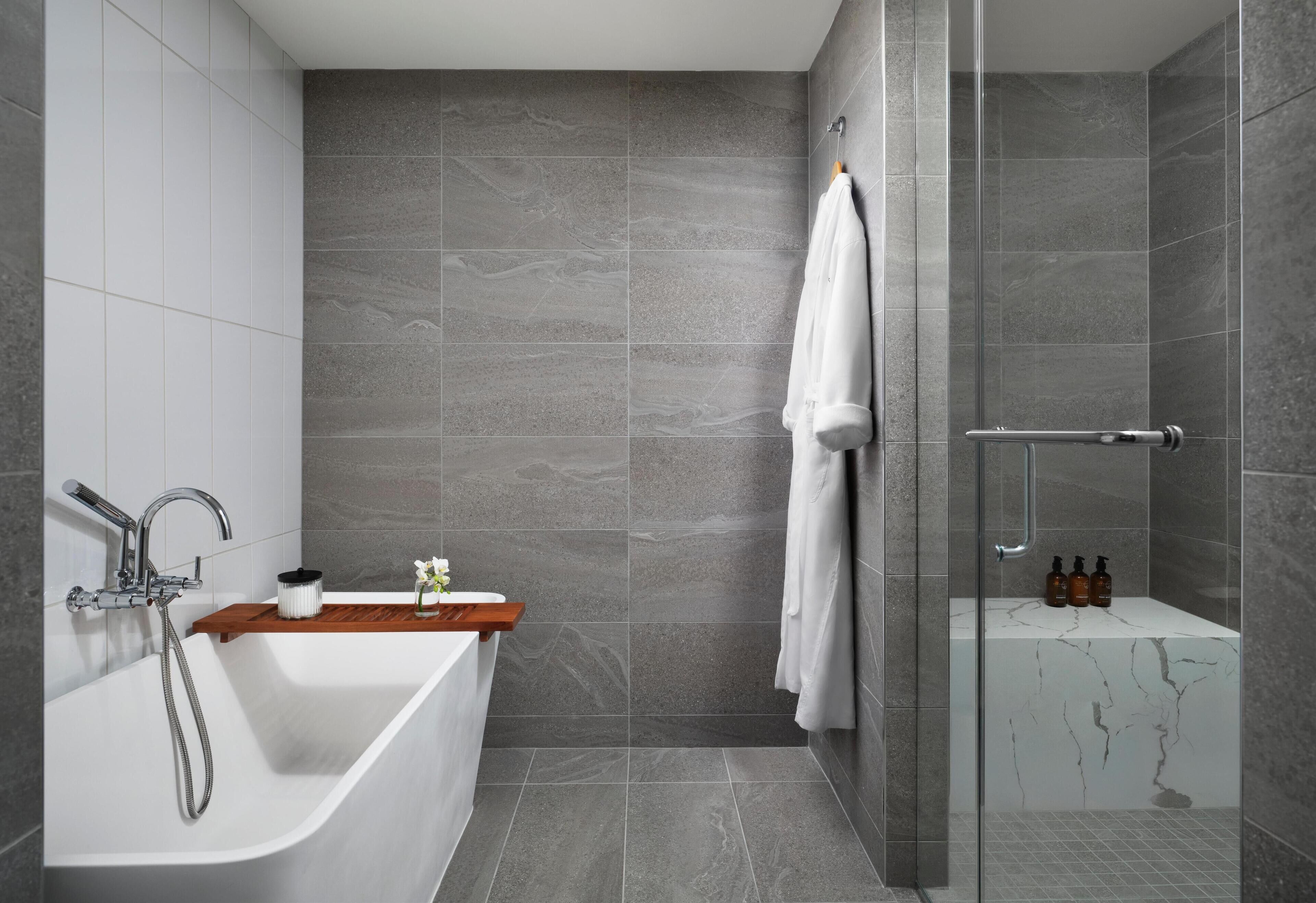 Une salle de bain moderne avec une baignoire sur pieds, une douche en verre et un meuble-lavabo en marbre.