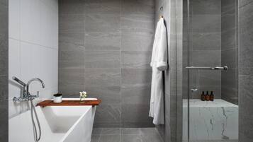 Une salle de bain moderne avec une baignoire sur pieds, une douche en verre et un meuble-lavabo en marbre.