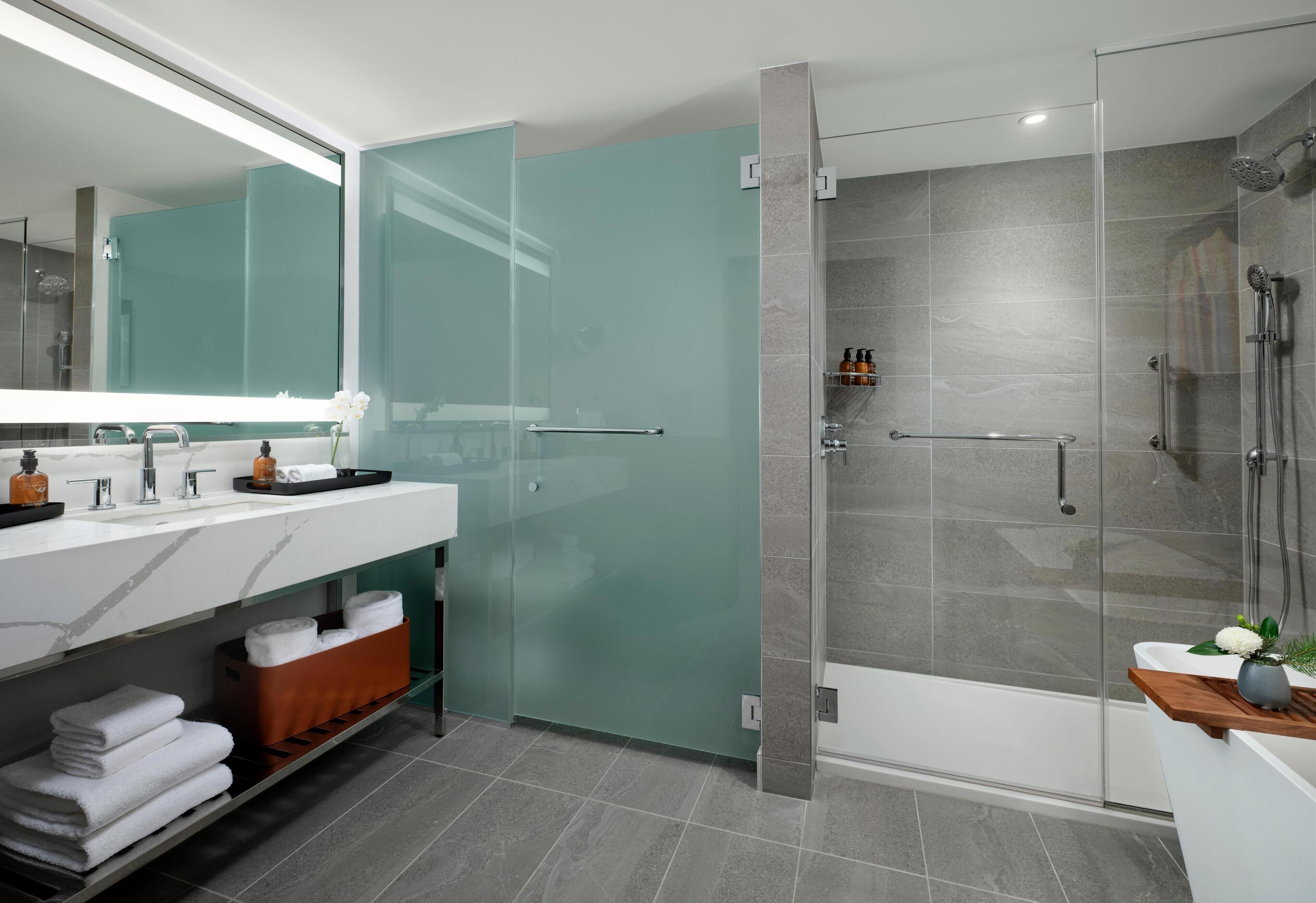 A modern bathroom with a glass shower enclosure, a vanity with a marble countertop, and a glass door shower.