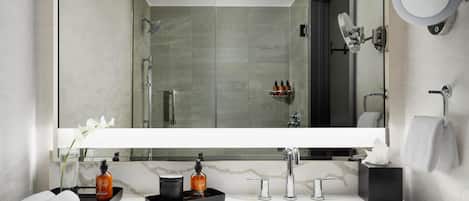 A modern bathroom with a large mirror, a sink, and a shower.