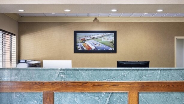 A reception desk with a marble top, wooden paneling, a monitor, and a doormat.