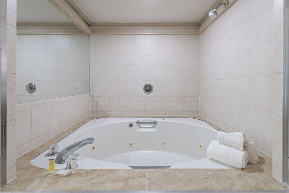 A large, freestanding bathtub in a bathroom with tiled walls and floor.