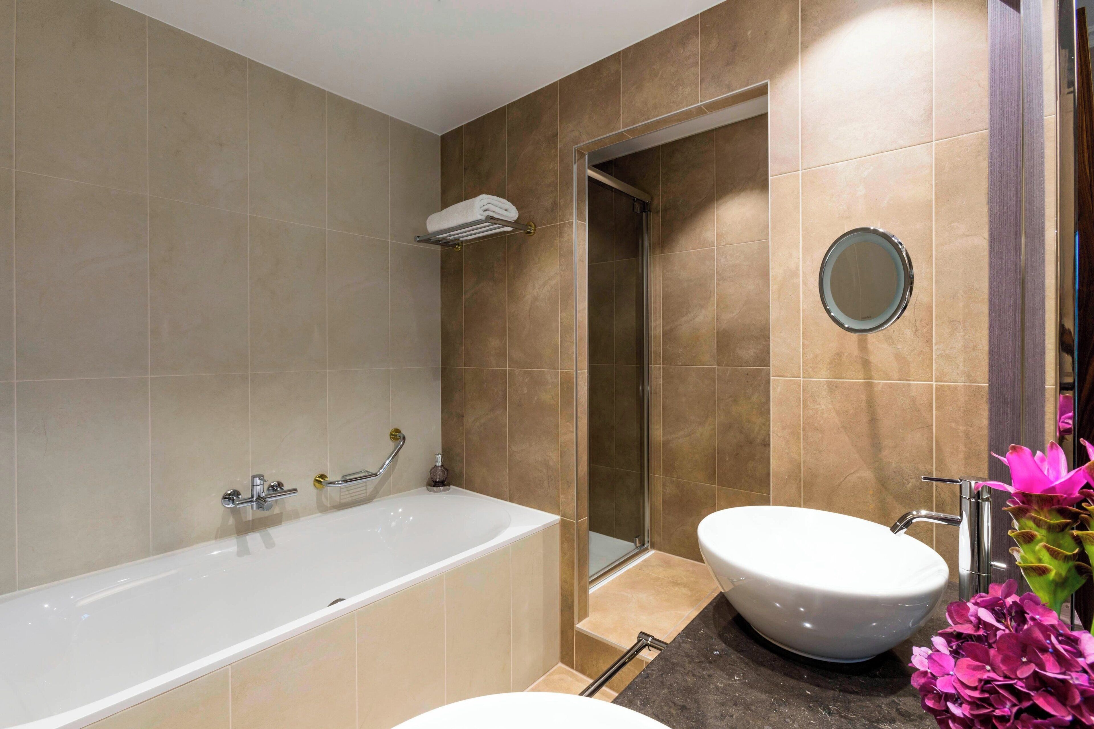 Een moderne badkamer met een bad, wastafel en douche.