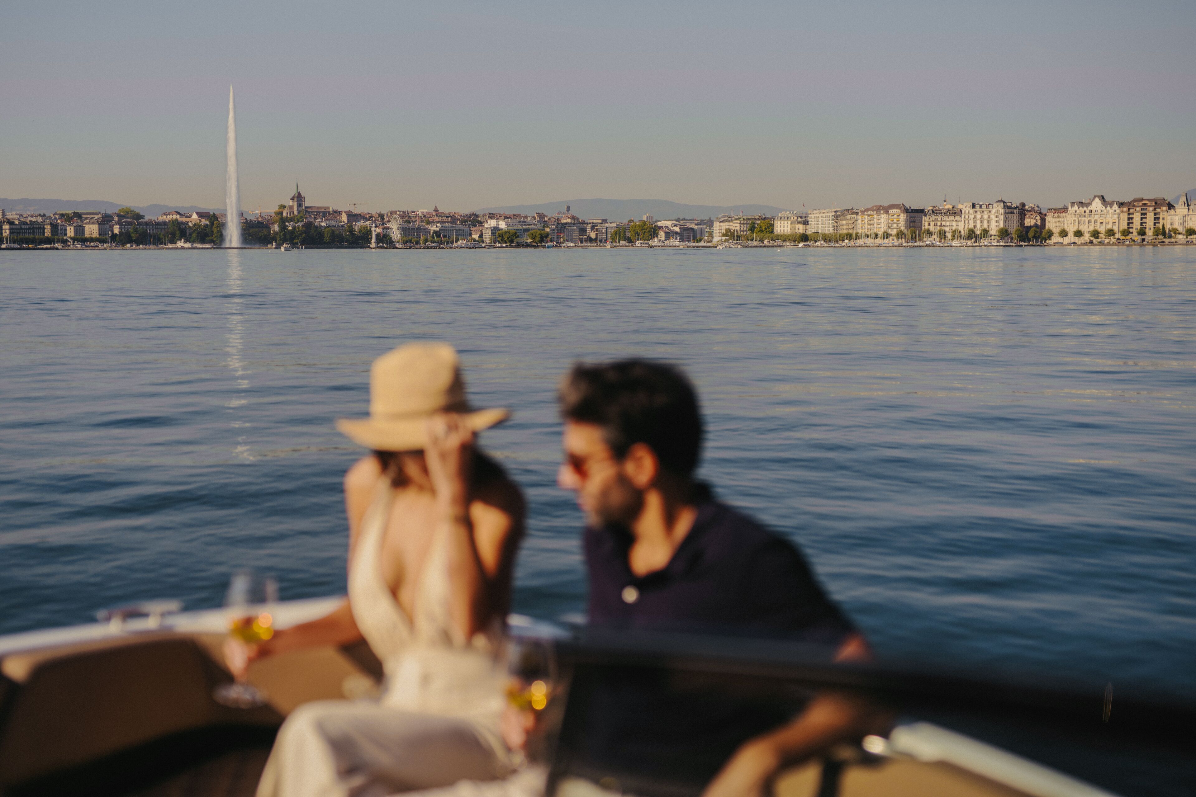 Un bateau avec deux personnes à bord, une vue sur une ville avec des bâtiments et une haute structure en arrière-plan.
