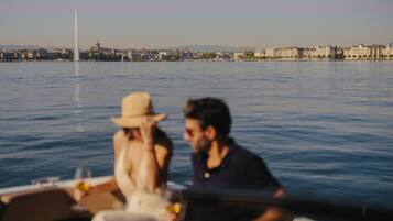 Un bote con dos personas a bordo, un paisaje urbano con edificios y una estructura alta al fondo.