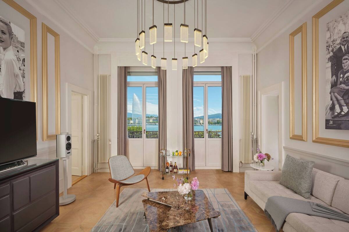 A spacious living room with a large TV, comfortable seating, a decorative table, and a view of a body of water through large windows.