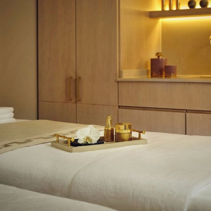 A hotel room with a neatly made bed, a tray with toiletries, and a mirror above the sink.