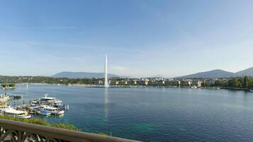 Blick auf das Wasser mit einem Brunnen, Booten und Gebäuden entlang des Ufers.
