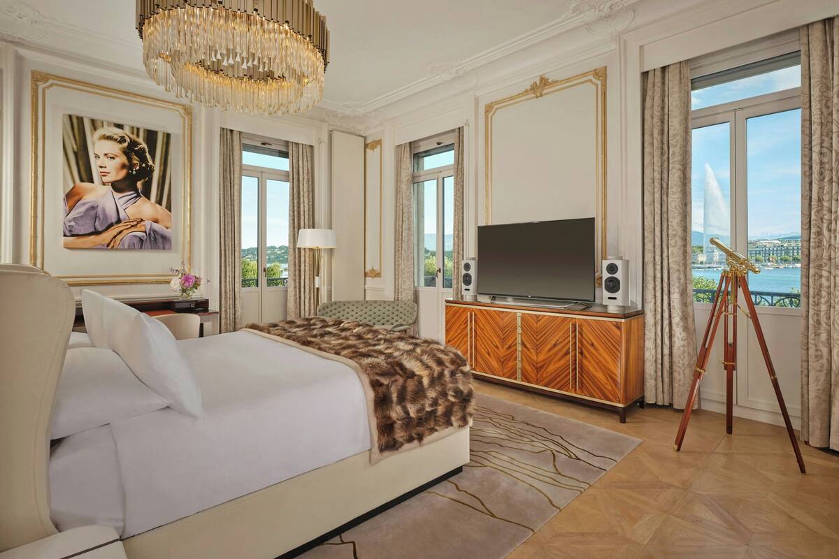 A luxurious hotel room with a large bed, a television, a wooden cabinet, and a tripod.