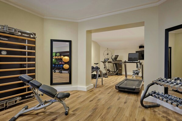 A gym with exercise equipment including a bench, treadmill, and dumbbells.