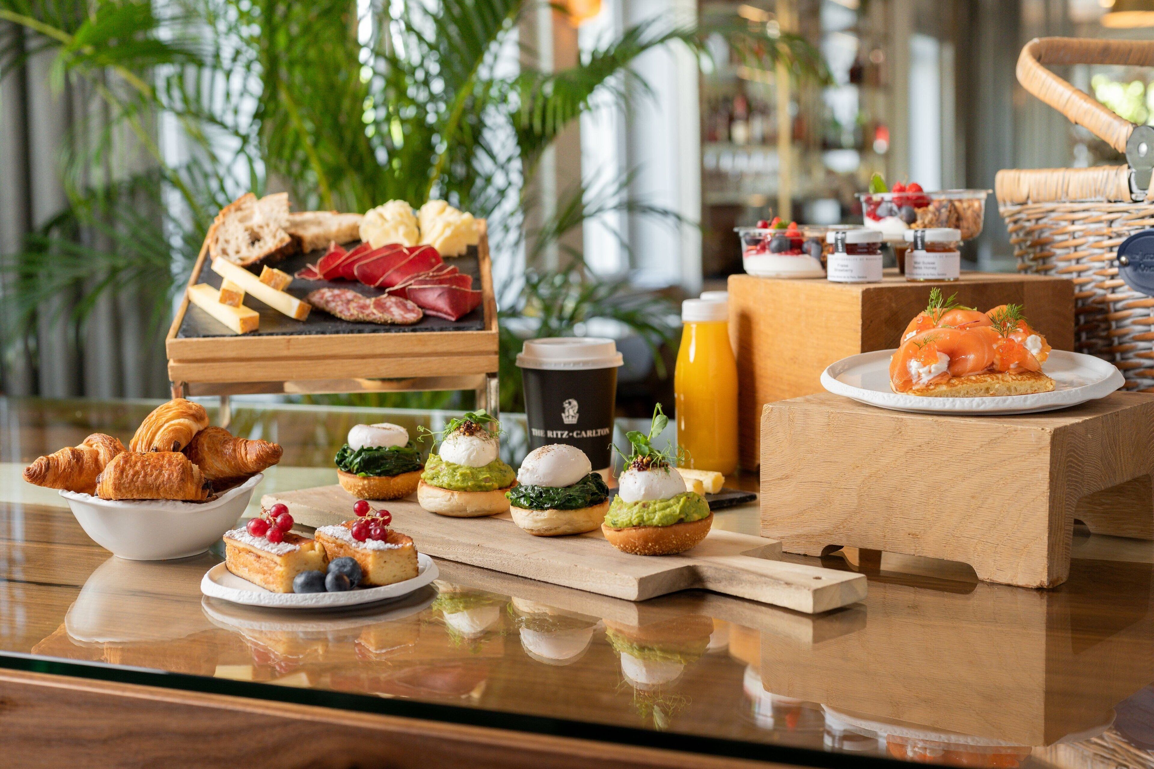 A breakfast buffet with various pastries, sandwiches, and a coffee station.