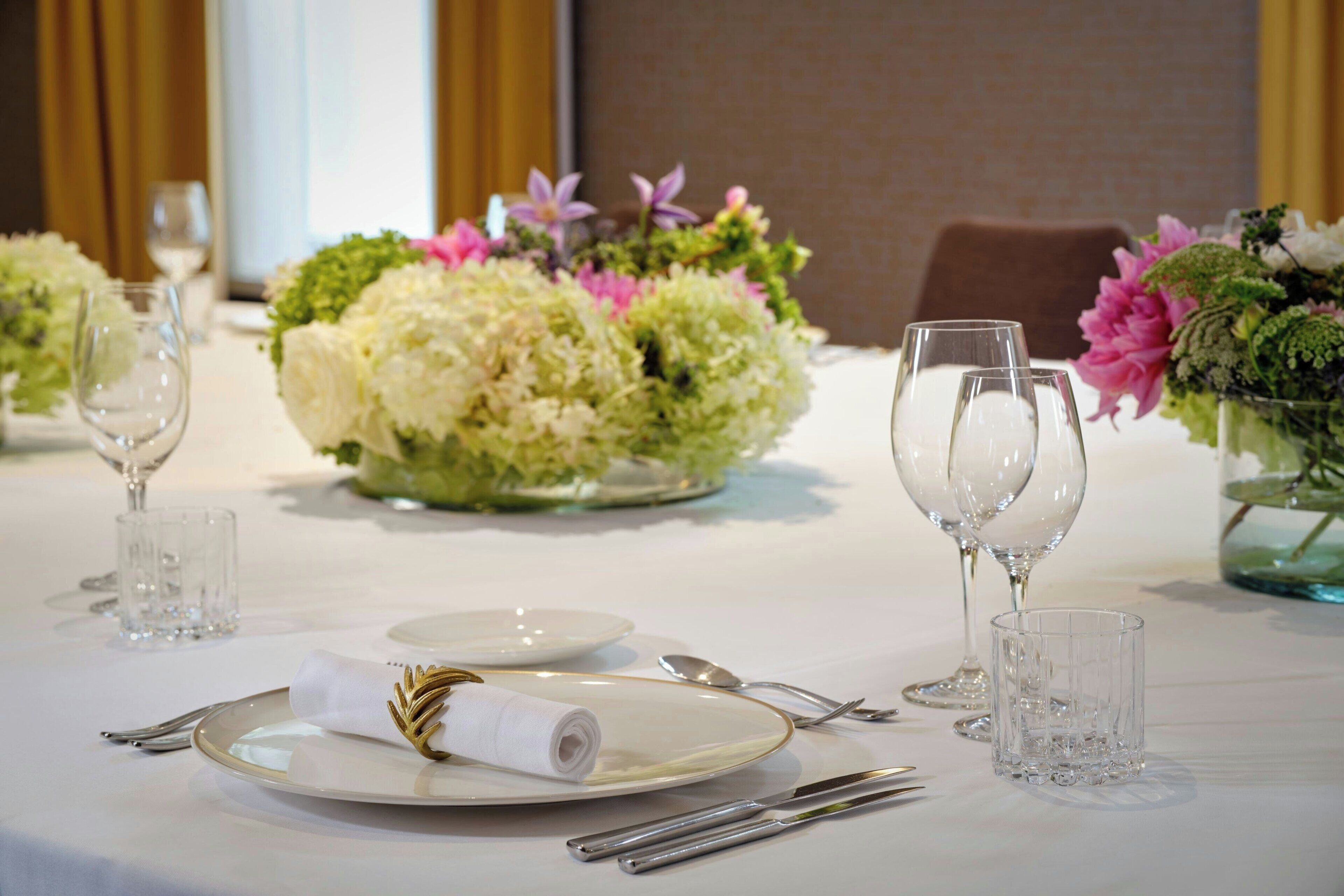 A table set for dining with white tablecloth, glassware, and floral centerpieces.