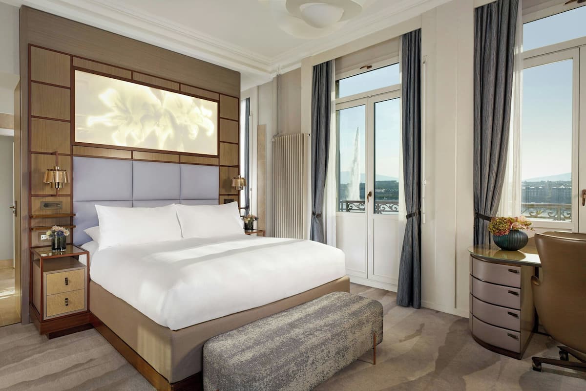 A spacious hotel room with a large bed, a desk, and a view of the city.