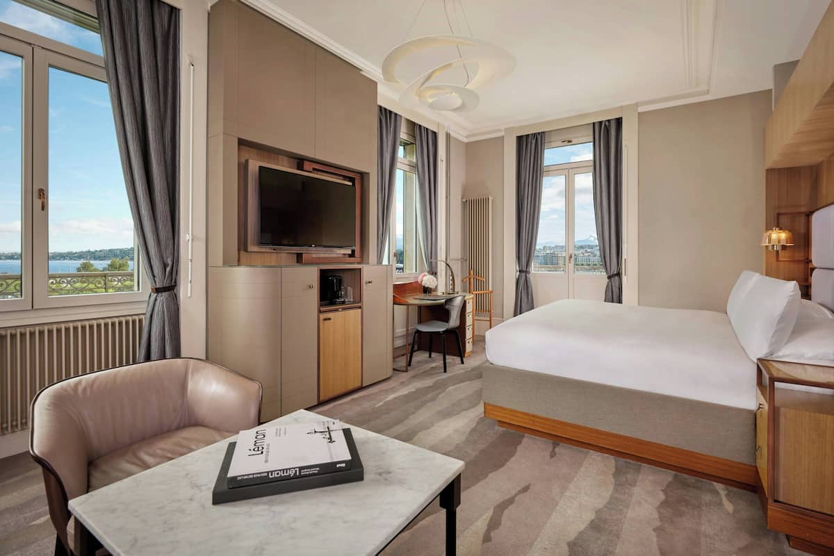 A hotel room with a bed, a desk, a TV, and a view of the outdoors.