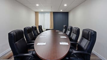 A conference room with a long table, black leather chairs, and a blue accent wall.