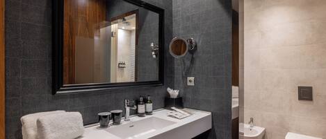 A modern bathroom with a large mirror, white sink, and a bidet.