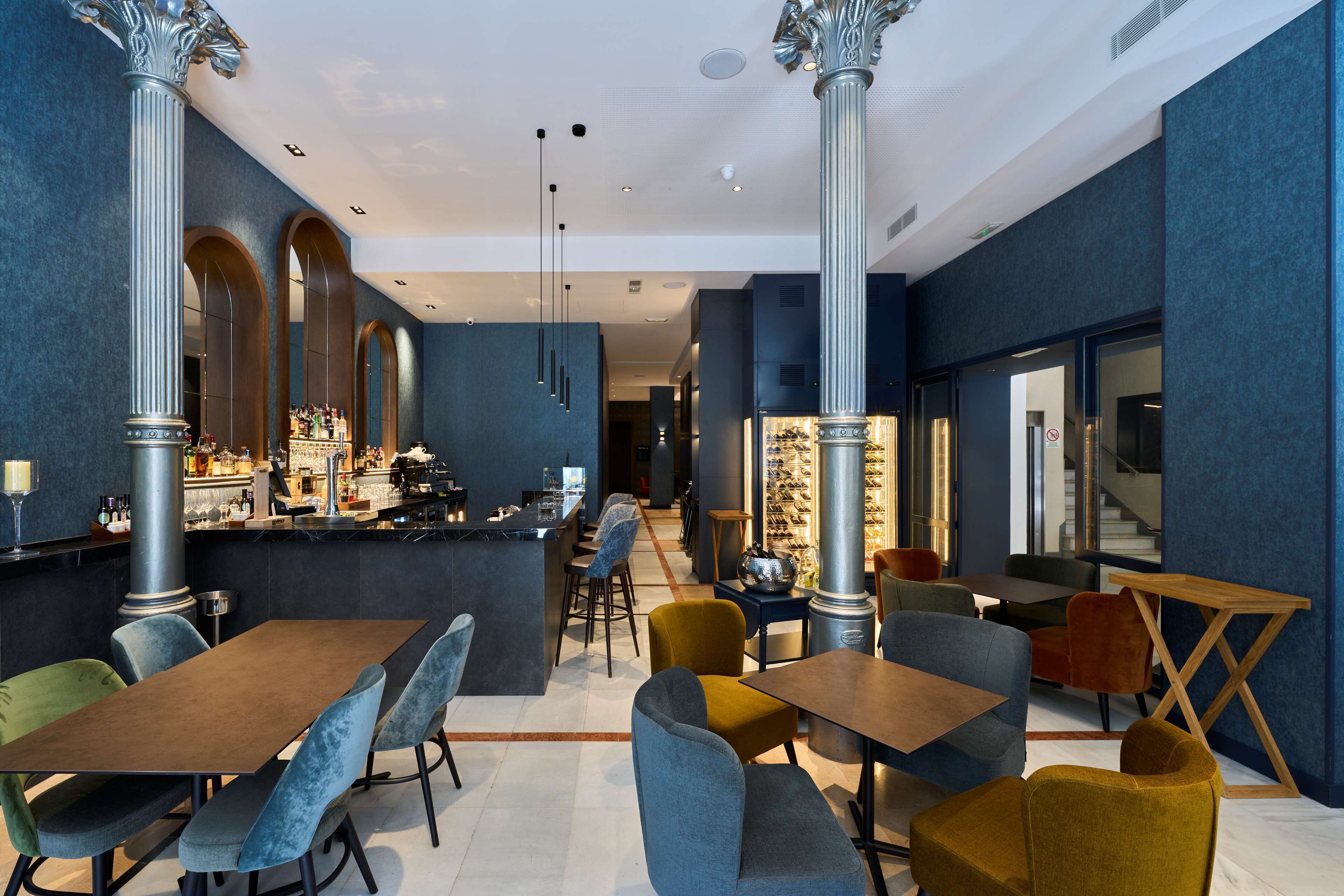 A modern interior with high ceilings, large columns, and a bar area.