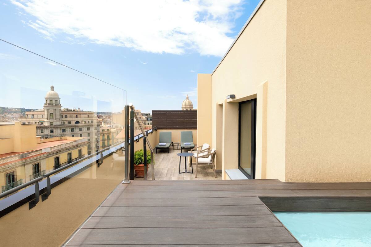 Terraço no telhado com piscina, área de estar e vista para edifícios históricos.