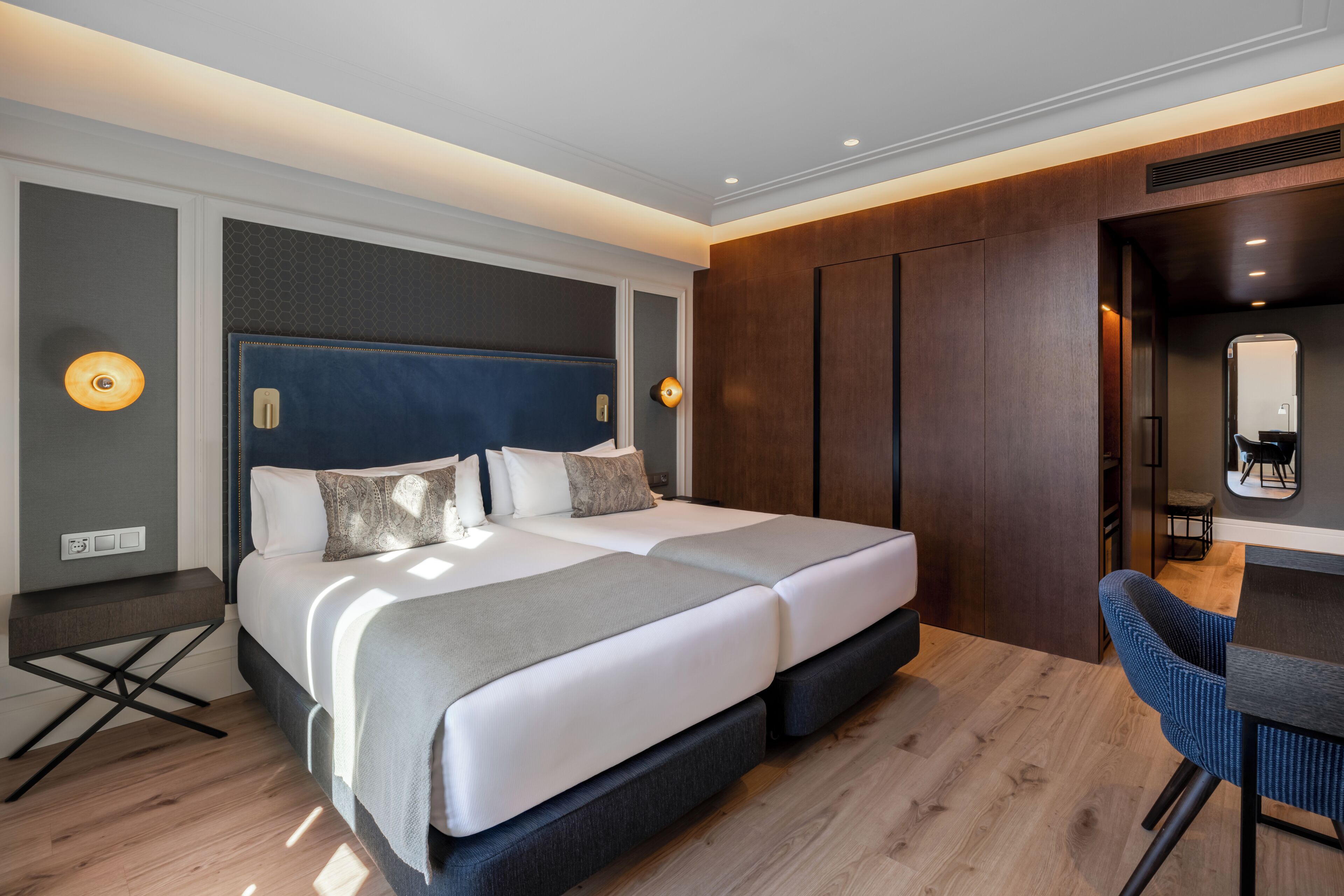A modern hotel room with a large bed, a desk, and a chair.