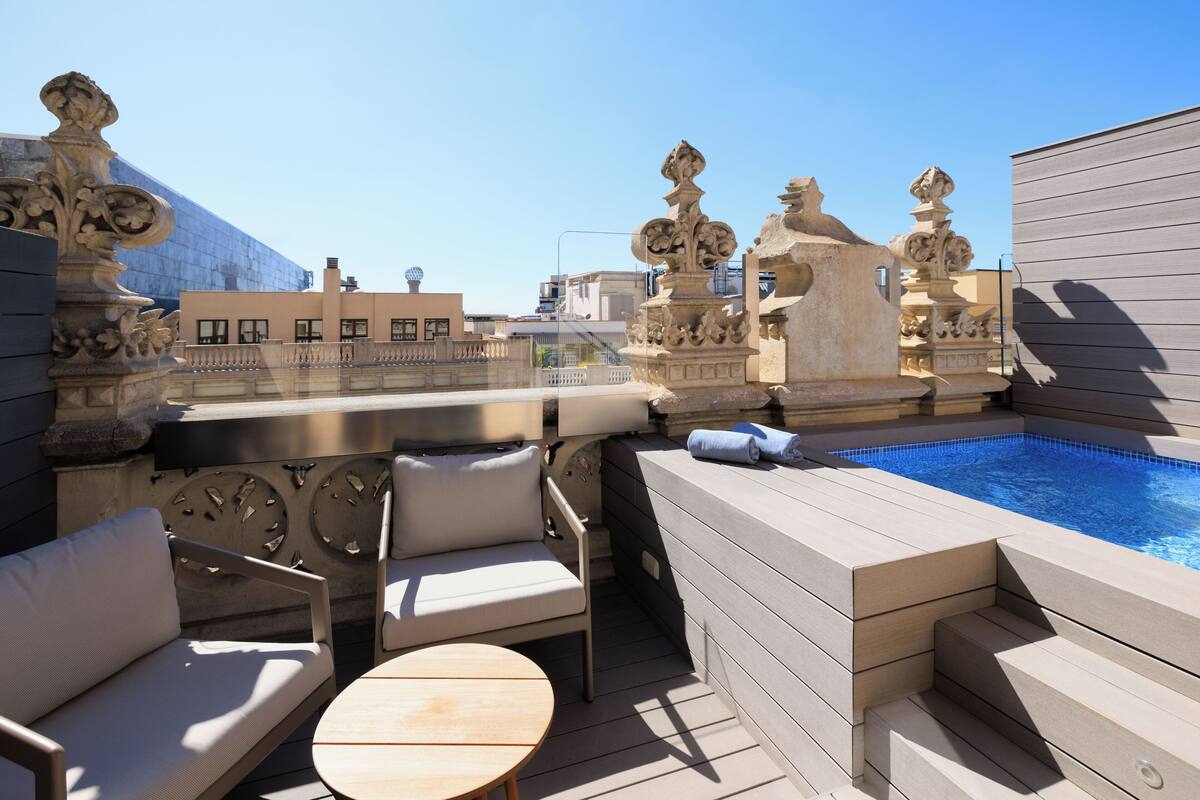 Terraço no telhado com piscina, área de estar externa e detalhes em pedra decorativa.