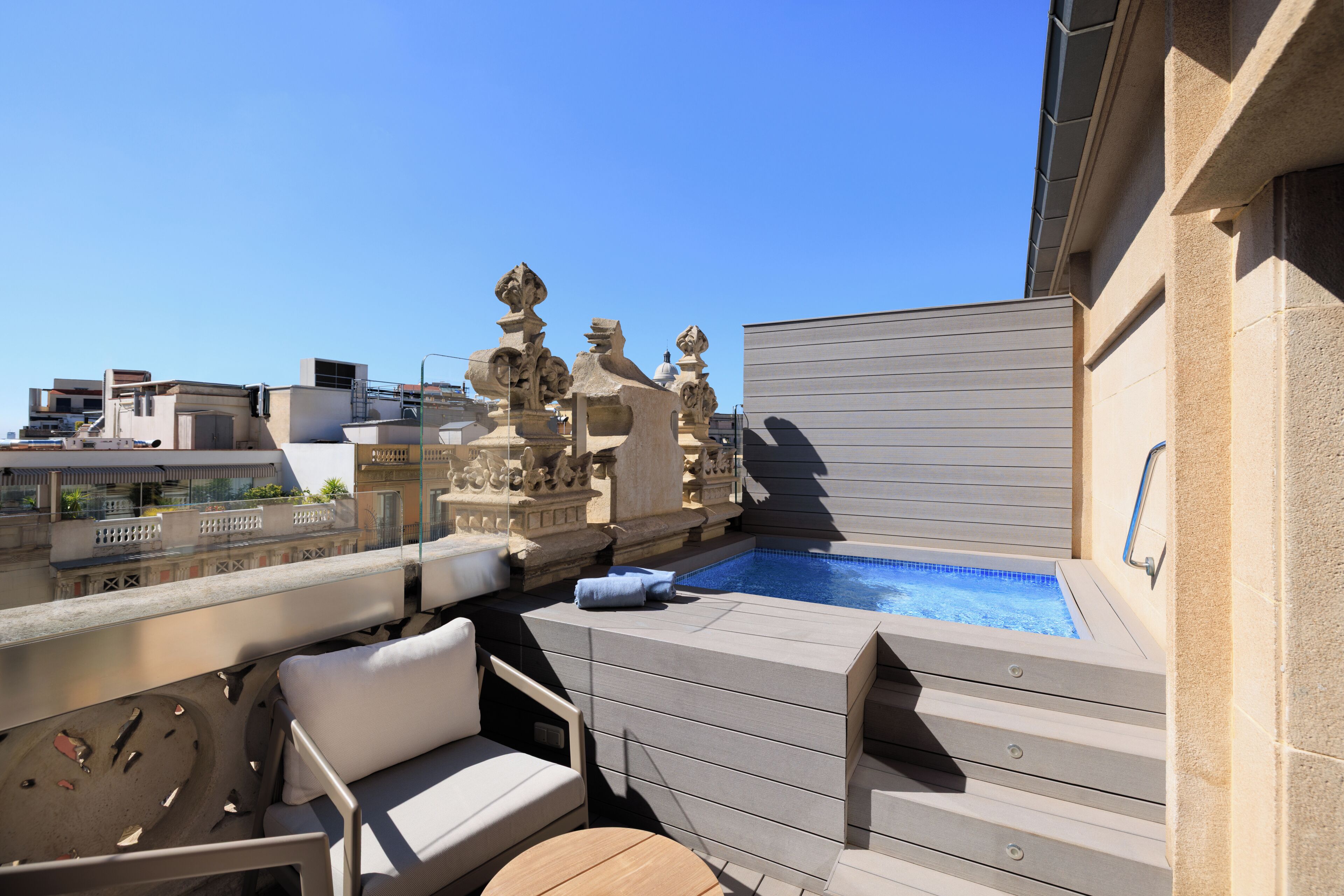 Una terraza en la azotea con piscina, mobiliario de exterior y detalles de piedra decorativa.