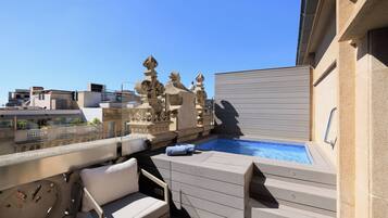 Una terraza en la azotea con piscina, mobiliario de exterior y detalles de piedra decorativa.