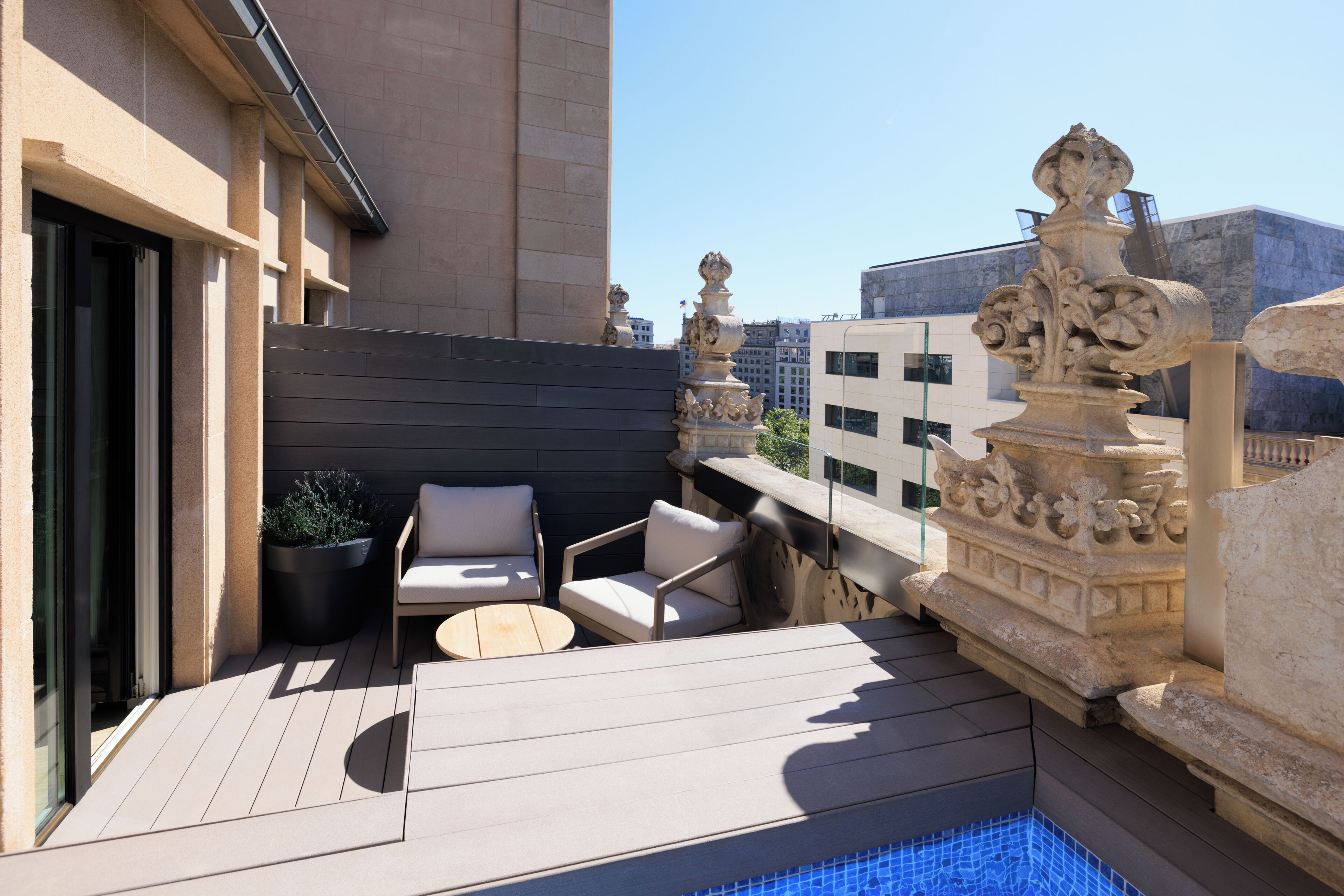 A rooftop terrace with outdoor seating, a pool, and a stone balustrade.