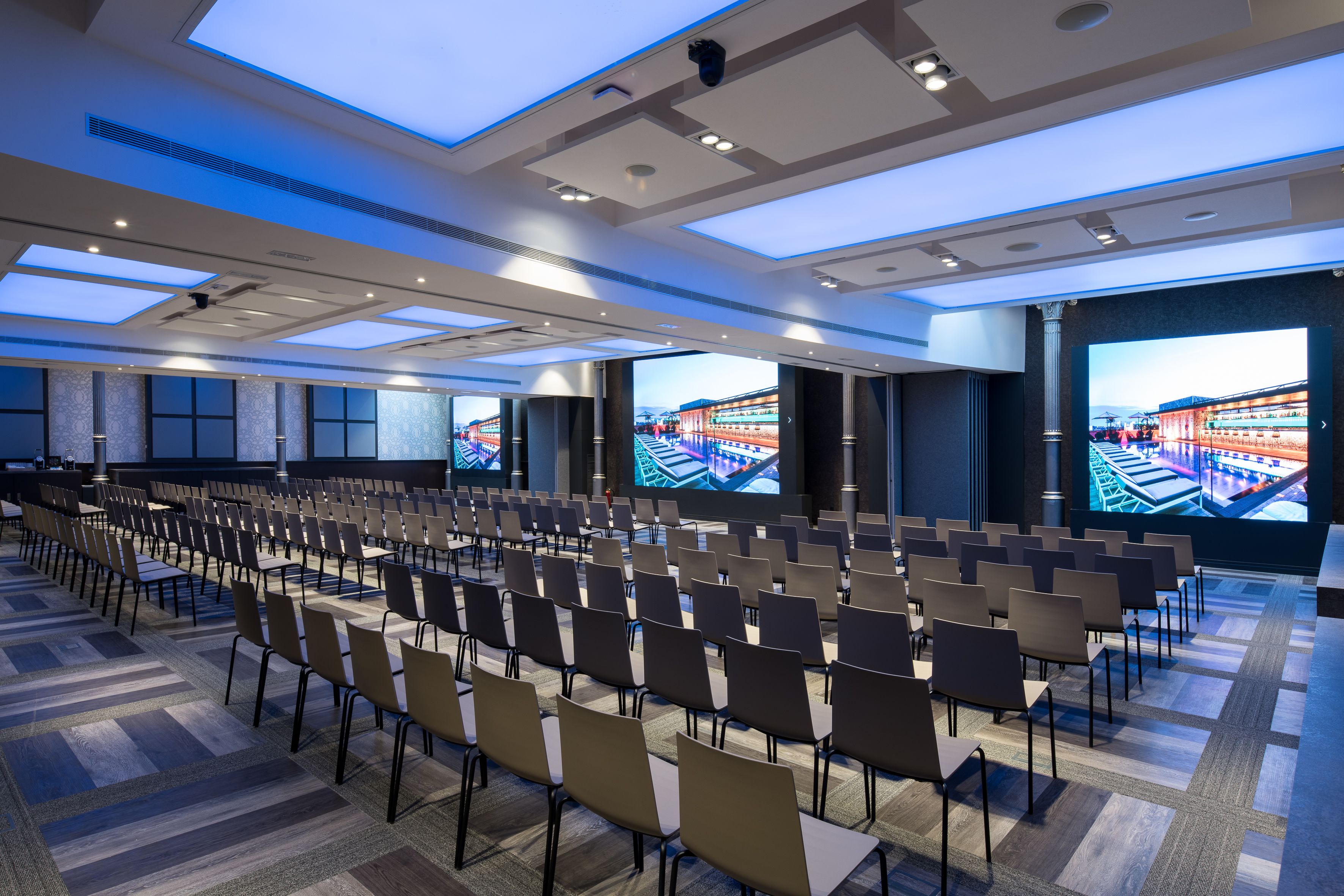 A conference room with rows of chairs, large windows, and a high ceiling with skylights.