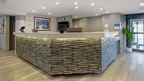A reception area with a stone-textured counter, a clock, and a framed cityscape poster.