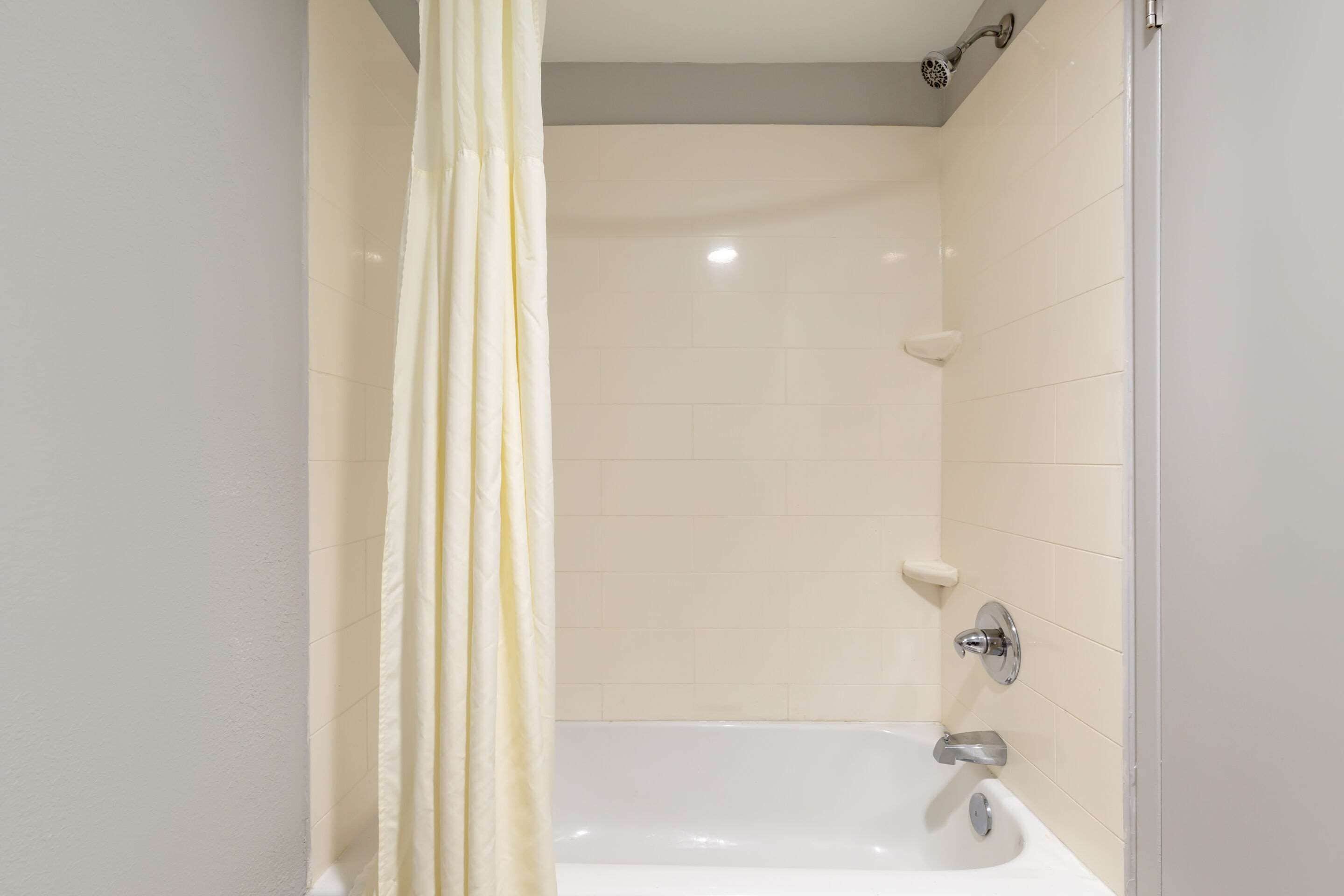 Un bagno con una vasca, una doccetta e un tendaggio.