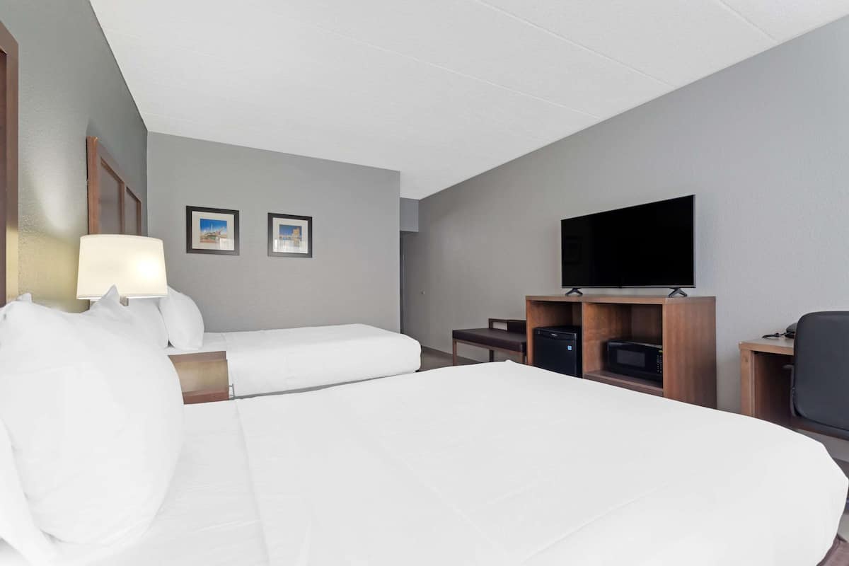 A hotel room with a large bed, a desk with a computer, a flat-screen TV, and a microwave.