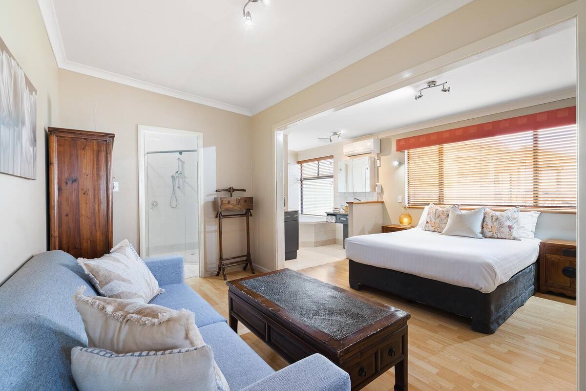 A spacious bedroom with a large bed, a sofa, and a wooden coffee table.