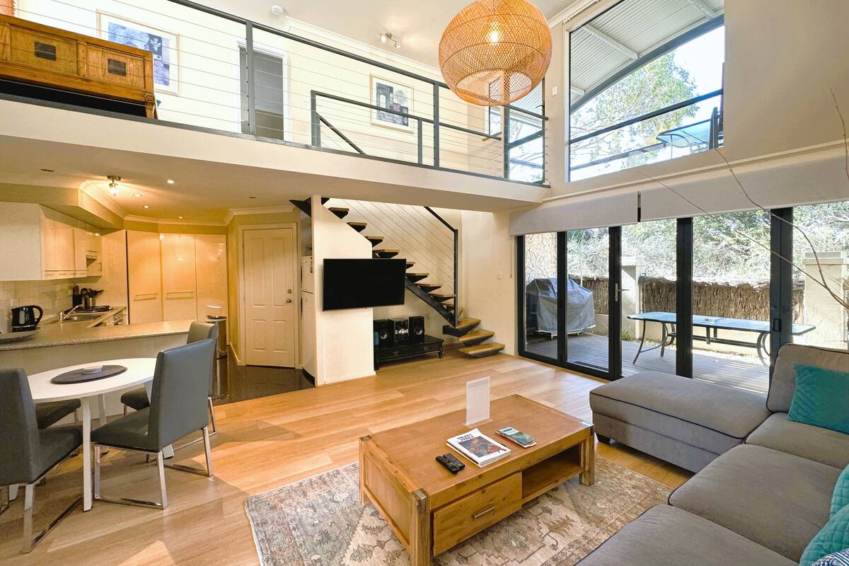 A spacious living area with a staircase, a dining area, and a kitchen.
