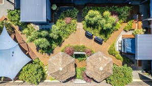 An aerial view of a modern building with a rooftop garden, wooden deck, and two large umbrellas. - Bay Village Resort Dunsborough (Dunsborough)