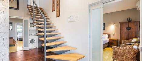 A modern interior with a wooden staircase, a laundry area, and a cozy seating area with wicker furniture.