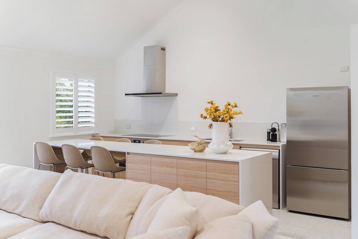 A modern kitchen with a central island, stainless steel appliances, and a dining area with chairs.