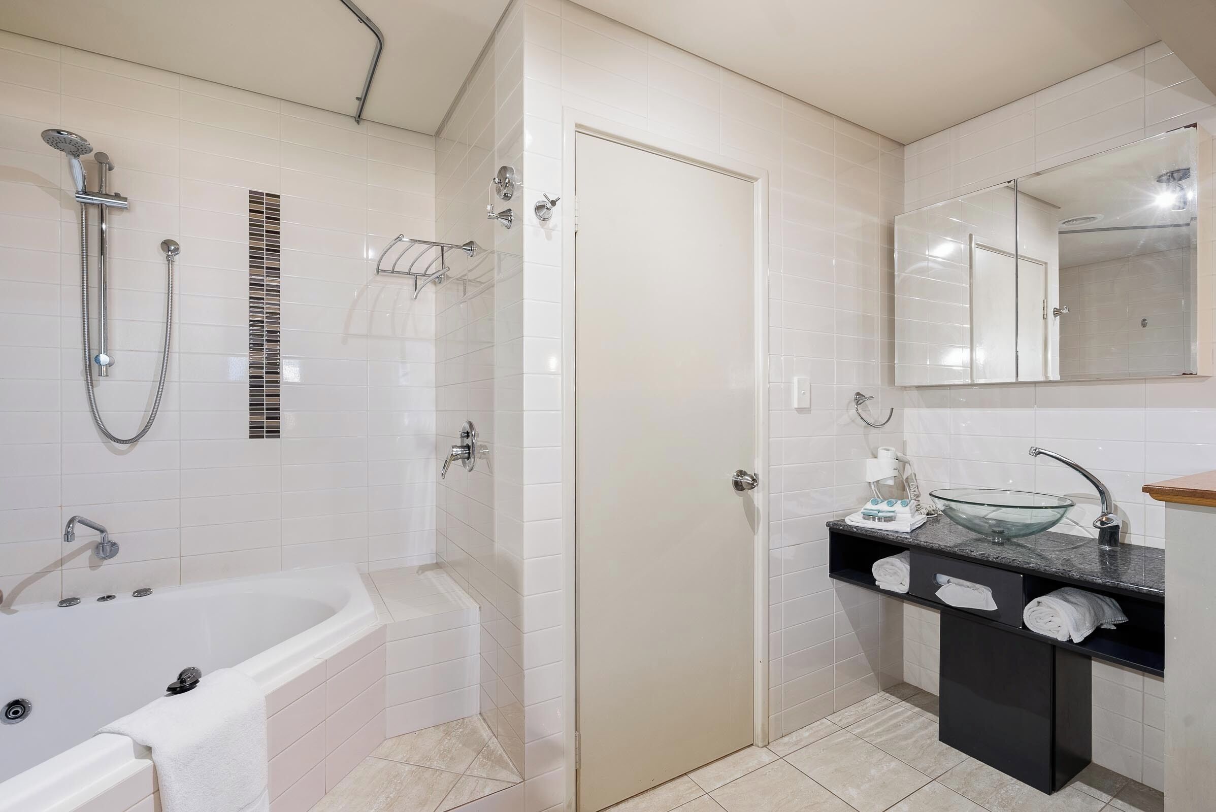 Une salle de bain moderne avec une baignoire, une douche et un lavabo en forme de bol en verre.