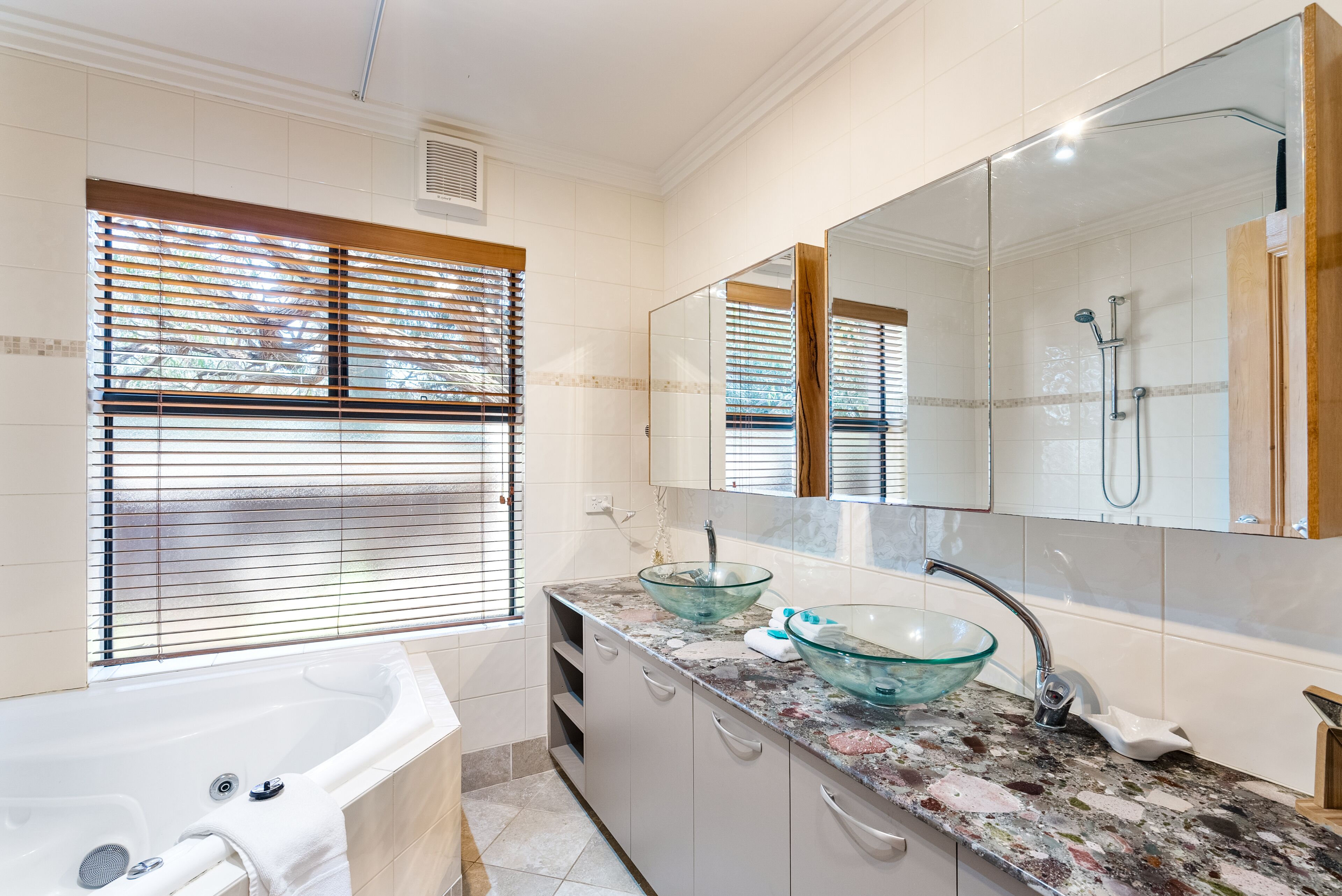 Een moderne badkamer met een wastafel van glas, een grote spiegel en een inloopdouche.