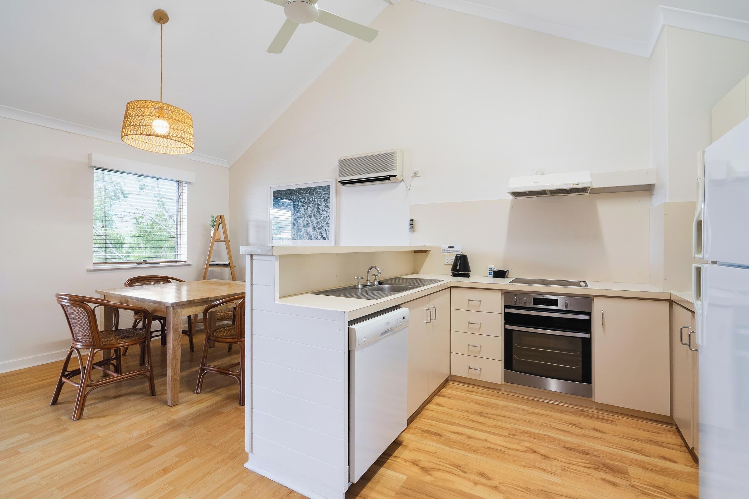 Una cocina compacta con lavavajillas, horno y comedor con sillas y mesa.