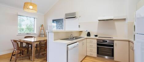 Una cocina compacta con lavavajillas, horno y comedor con sillas y mesa.