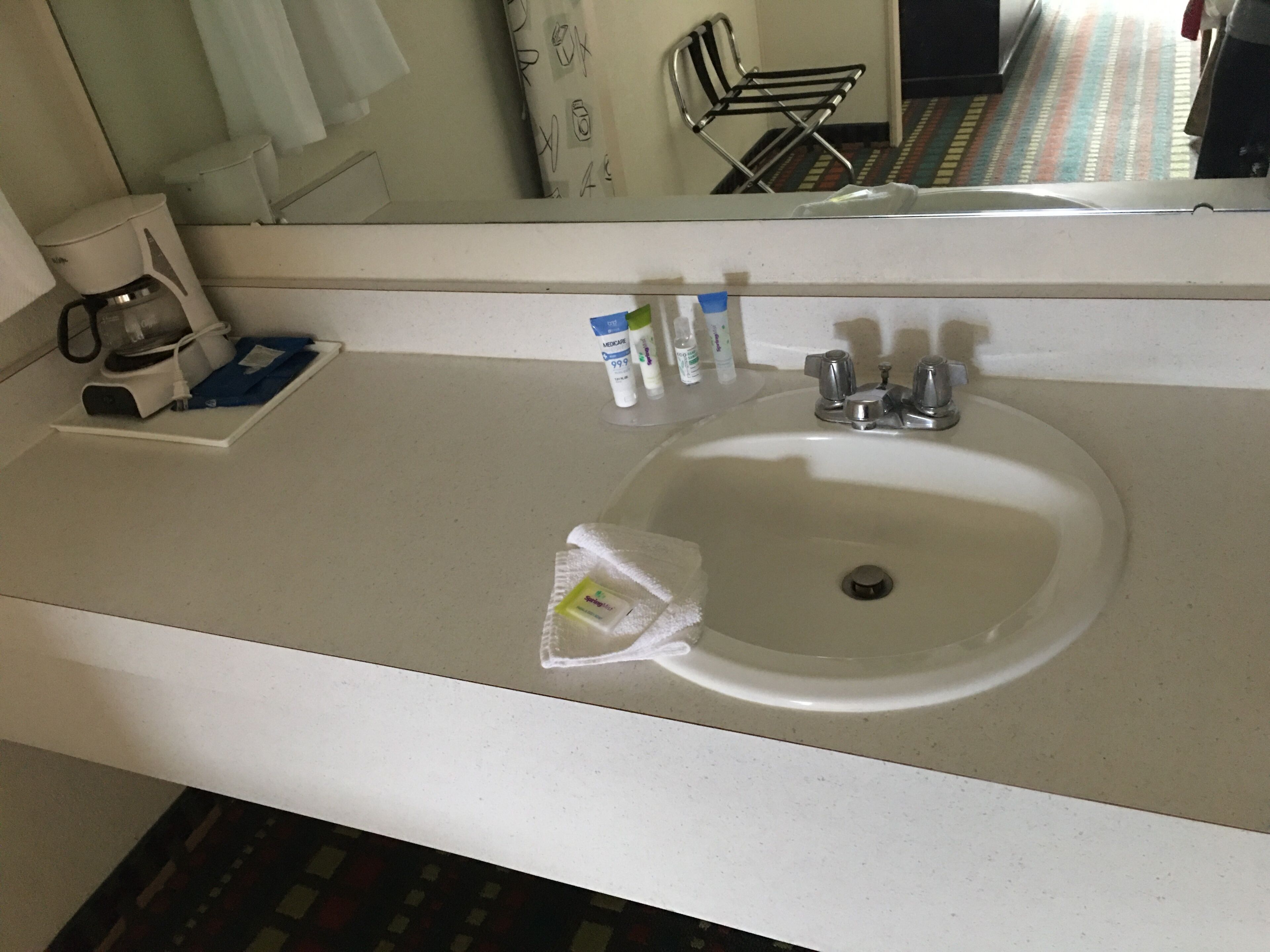 A bathroom with a white sink, a mirror, and toiletries on the counter.