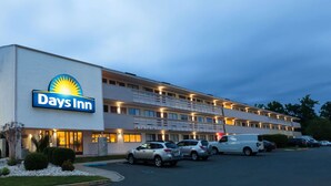 Un hotel Days Inn con un estacionamiento amplio y varios autos estacionados al frente.
