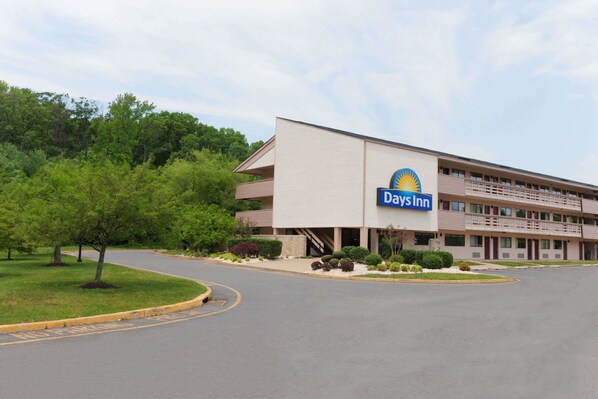 Un hotel Days Inn con un diseño moderno, que cuenta con un letrero grande, un estacionamiento y zonas verdes circundantes.
