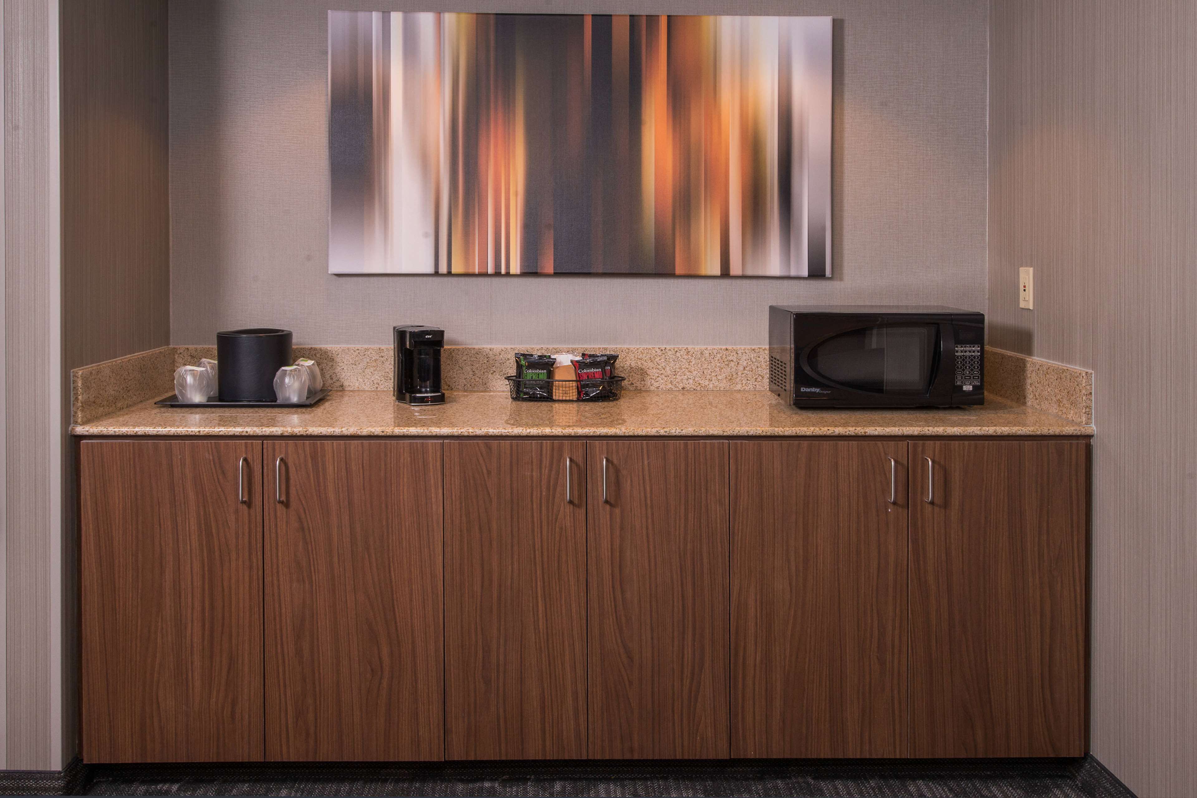 A kitchenette with a microwave, coffee maker, and a coffee dispenser.