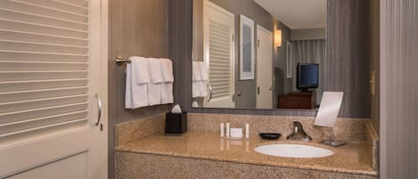 A modern bathroom with a granite countertop, a white sink, a mirror, and a towel rack.