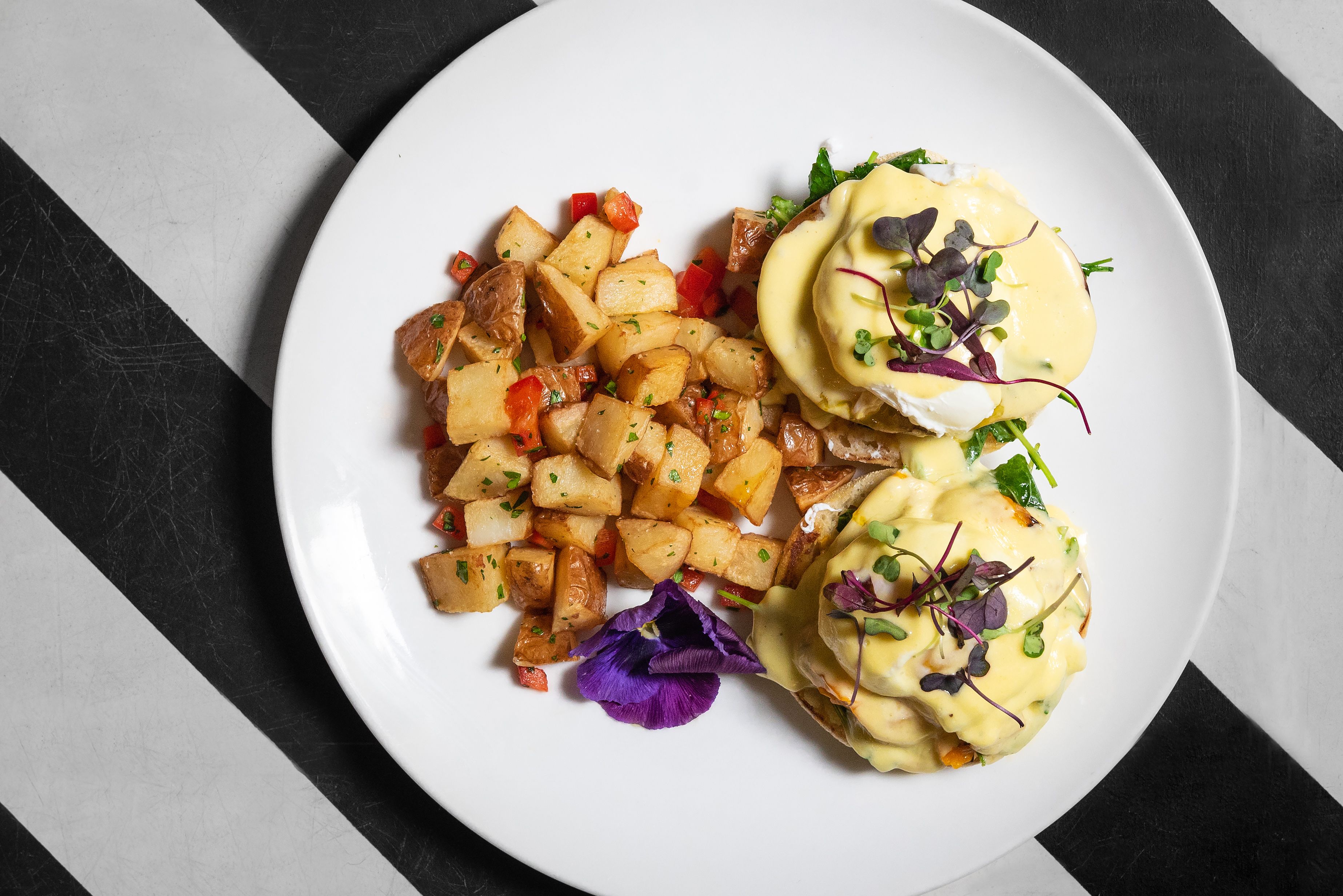 A plate with roasted potatoes, a poached egg, and a green sauce garnish.