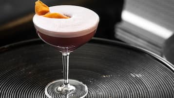 Un cocktail servi dans un verre à martini, posé sur une surface noire texturée.