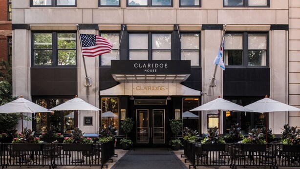 The Claridge House building with a sign, American and another flag, and outdoor seating with umbrellas. - Claridge House Chicago, Tapestry Collection by Hilton (Chicago)