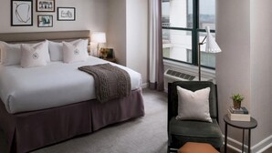 A modern hotel room with a large bed, a chair, a small table, and a window with a view. - Claridge House Chicago, Tapestry Collection by Hilton (Chicago)